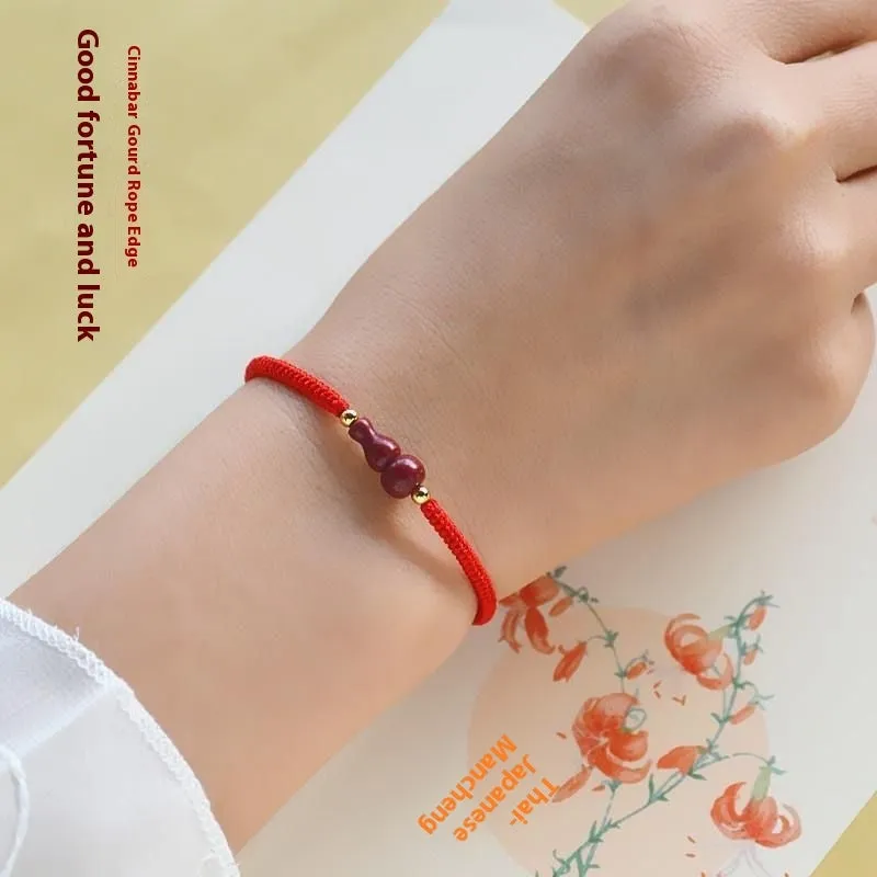 Traditional cinnabar bracelet with a heart-shaped peace buckle clasp on a red rope.