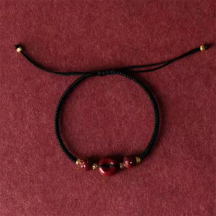 Traditional cinnabar bracelet with a heart-shaped peace buckle clasp on a red rope.