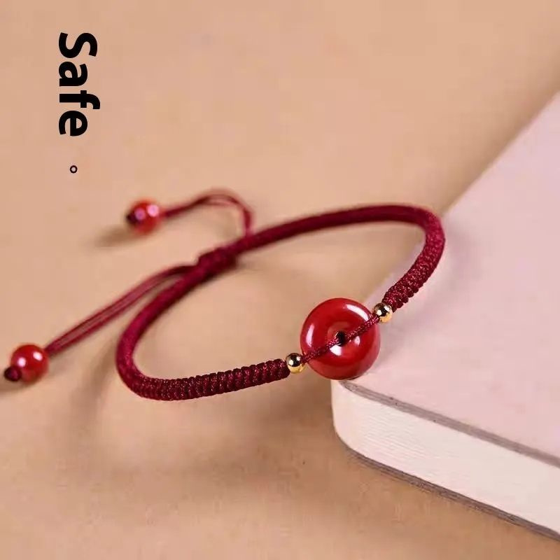 Traditional cinnabar bracelet with a heart-shaped peace buckle clasp on a red rope.