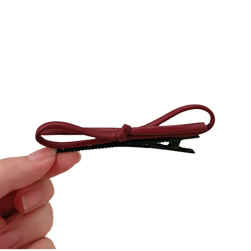 Wine red leather bow hair barrette on a white background.