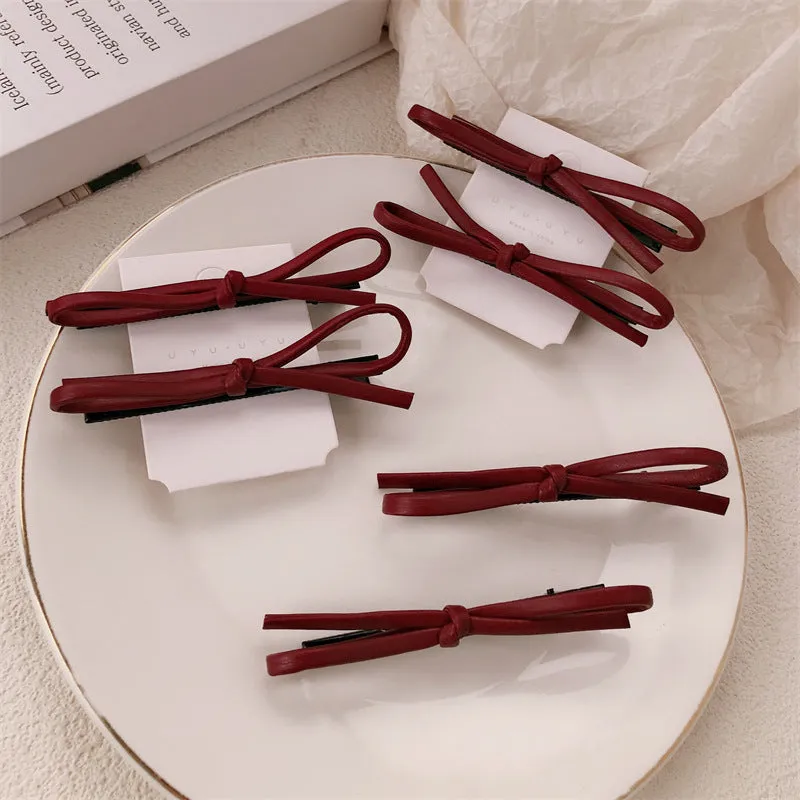 Wine red leather bow hair barrette on a white background.