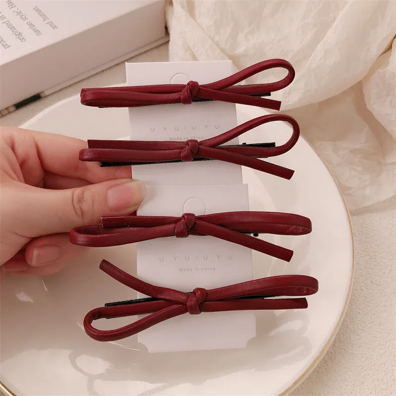 Wine red leather bow hair barrette on a white background.