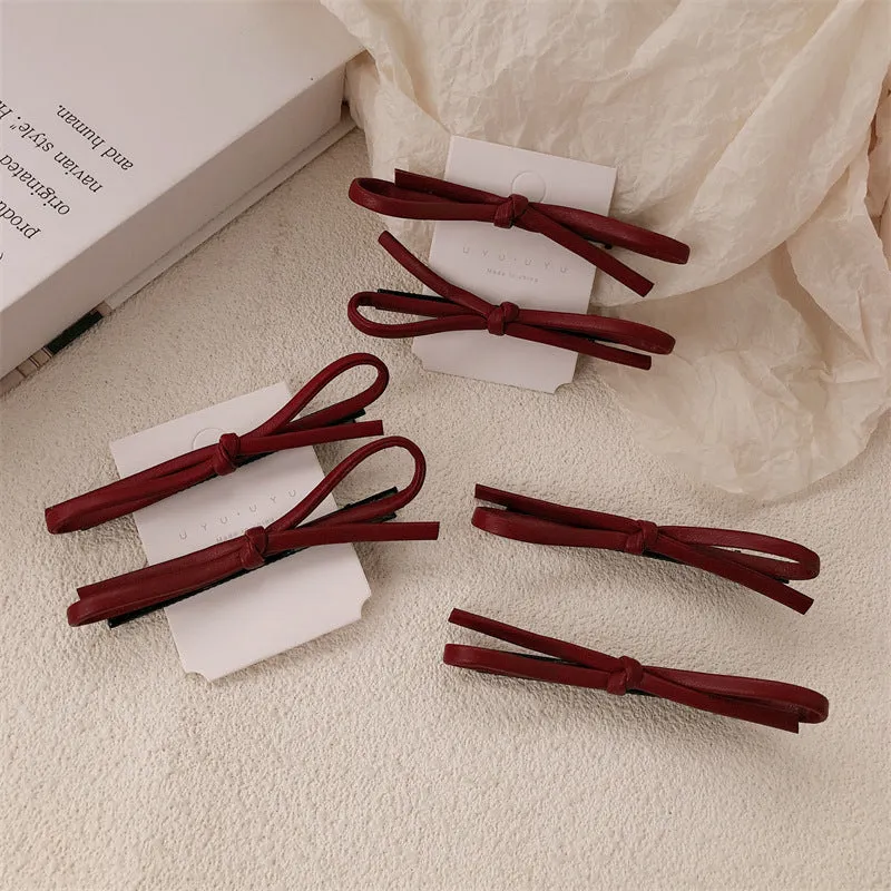 Wine red leather bow hair barrette on a white background.