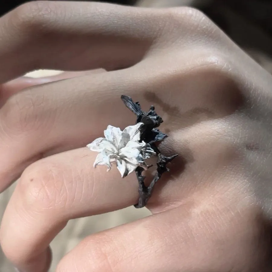 Open mouth copper ring with white and black colour separation and lily motif on a plain background