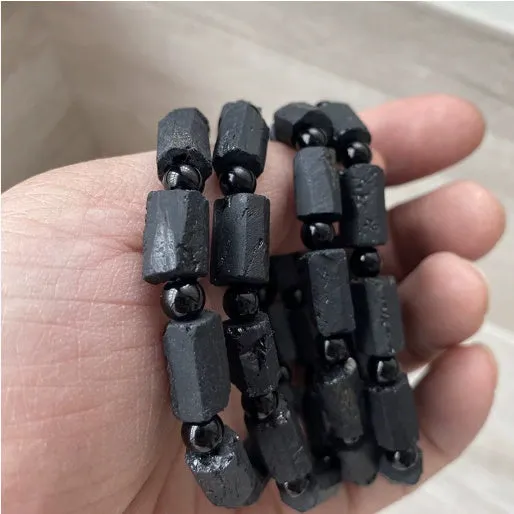 Black tourmaline rough stone bracelet on a wrist, showing natural texture and 10mm size