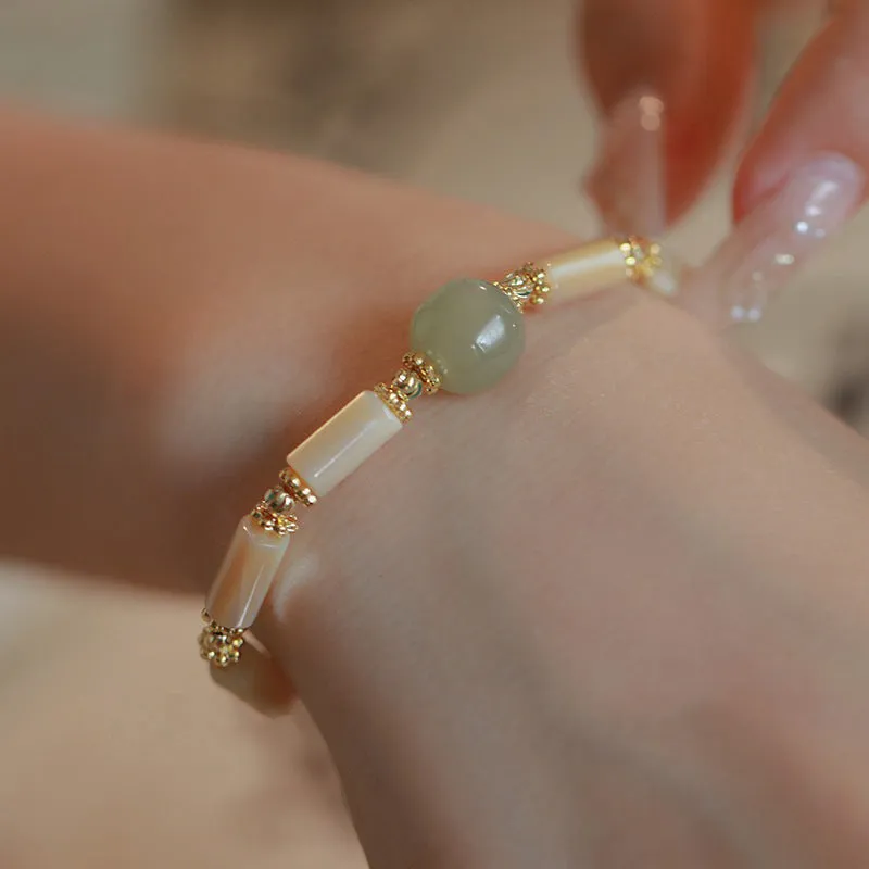 Simple women's bracelet made of round white Hetian jade beads on a wrist.