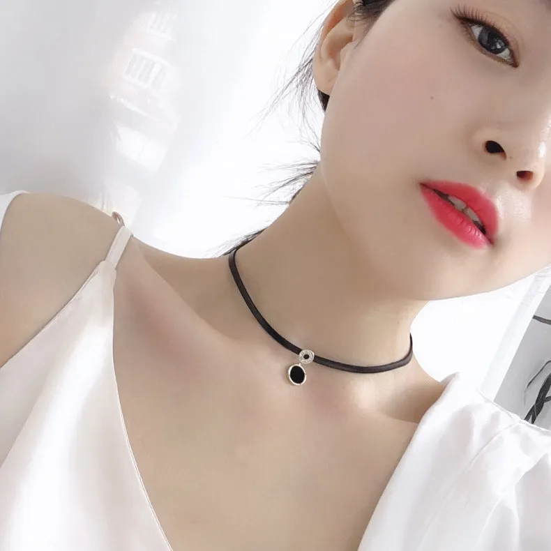 Women's short black clavicle necklace with round gold alloy pendant and leather rope chain on display