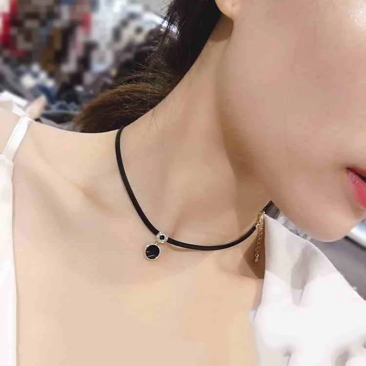 Women's short black clavicle necklace with round gold alloy pendant and leather rope chain on display