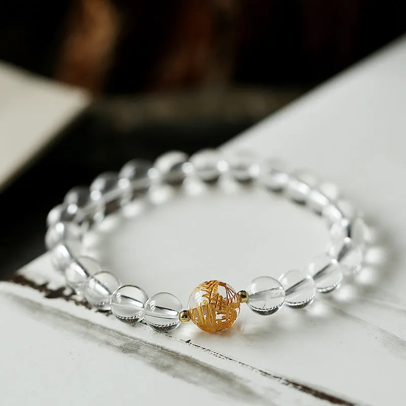 Geometric obsidian and white crystal bracelet with a golden dragon focal bead on a wrist.