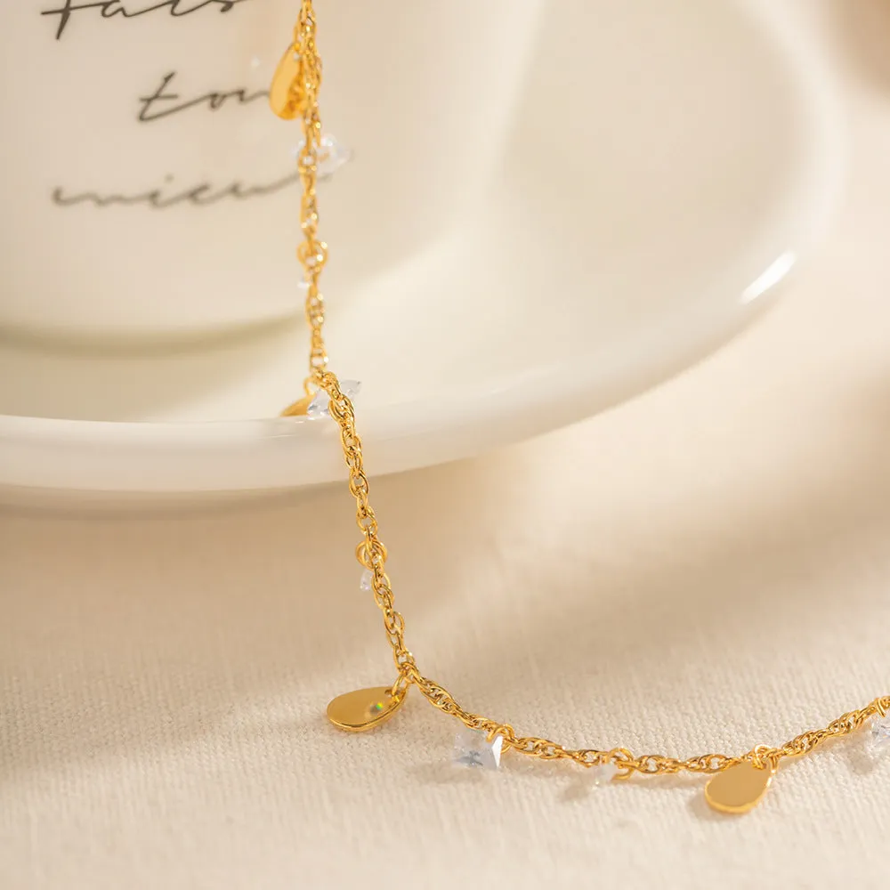 Stainless steel women's anklet with a geometric water drop tassel charm on an ankle.