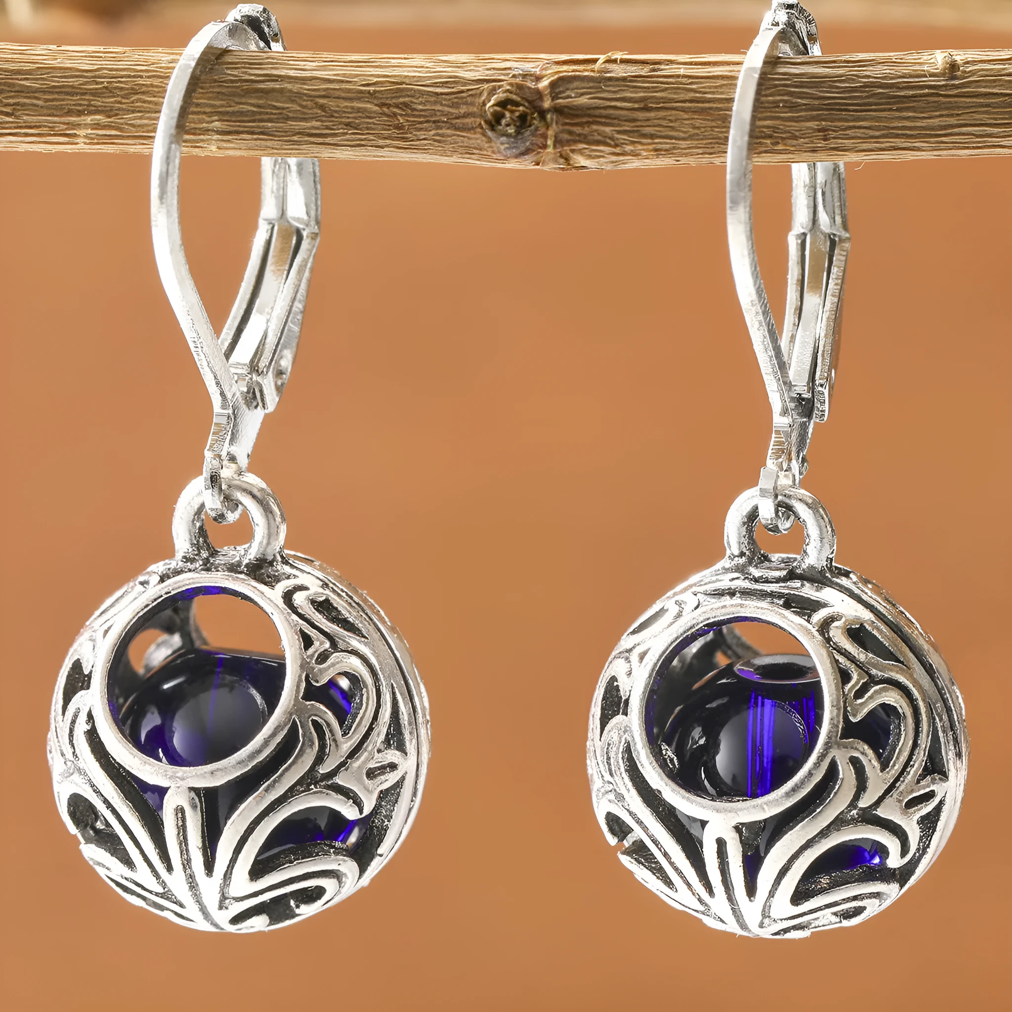 Silver tone geometric earrings with hollow pendant designs and blue gemstone accents