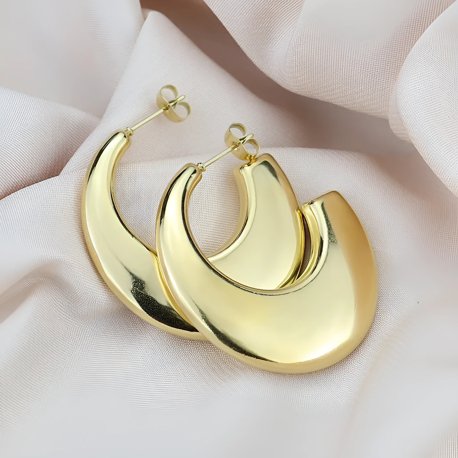 Two pairs of geometric thread stud earrings in gold and steel colour on a flat surface