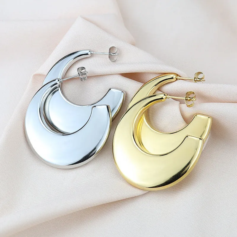 Two pairs of geometric thread stud earrings in gold and steel colour on a flat surface