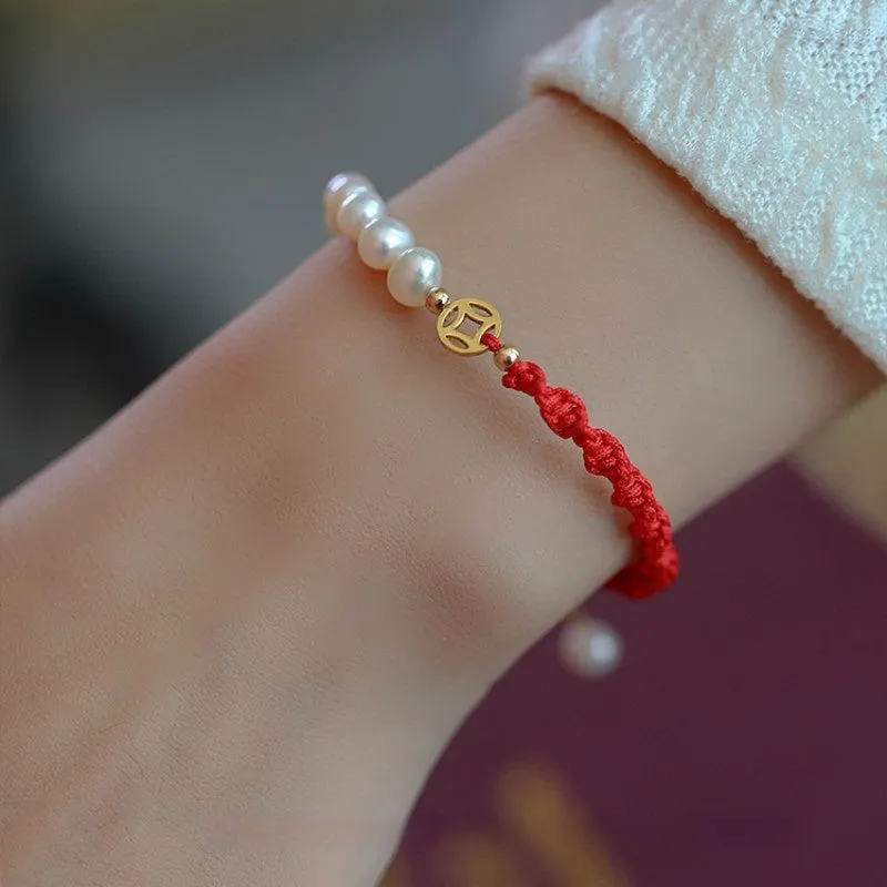 Close-up of a women's pearl and braided red rope bracelet with a gold-plated geometric fu character charm.