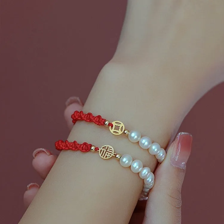 Close-up of a women's pearl and braided red rope bracelet with a gold-plated geometric fu character charm.