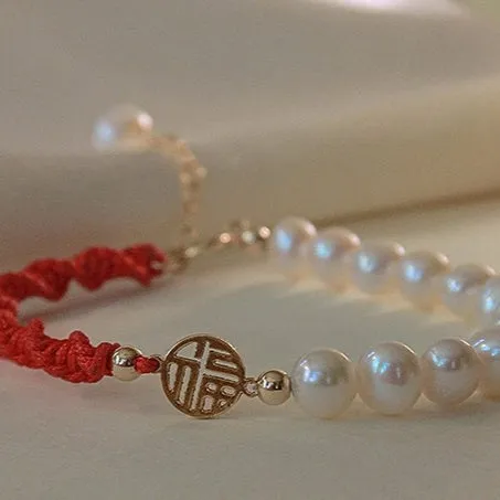 Close-up of a women's pearl and braided red rope bracelet with a gold-plated geometric fu character charm.