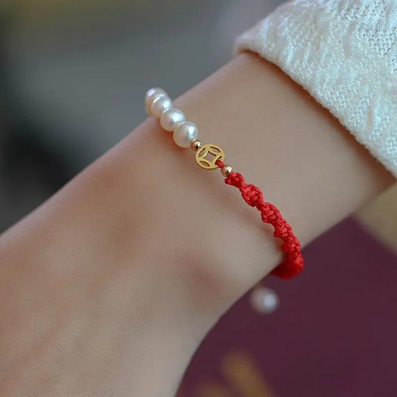 Close-up of a women's pearl and braided red rope bracelet with a gold-plated geometric fu character charm.