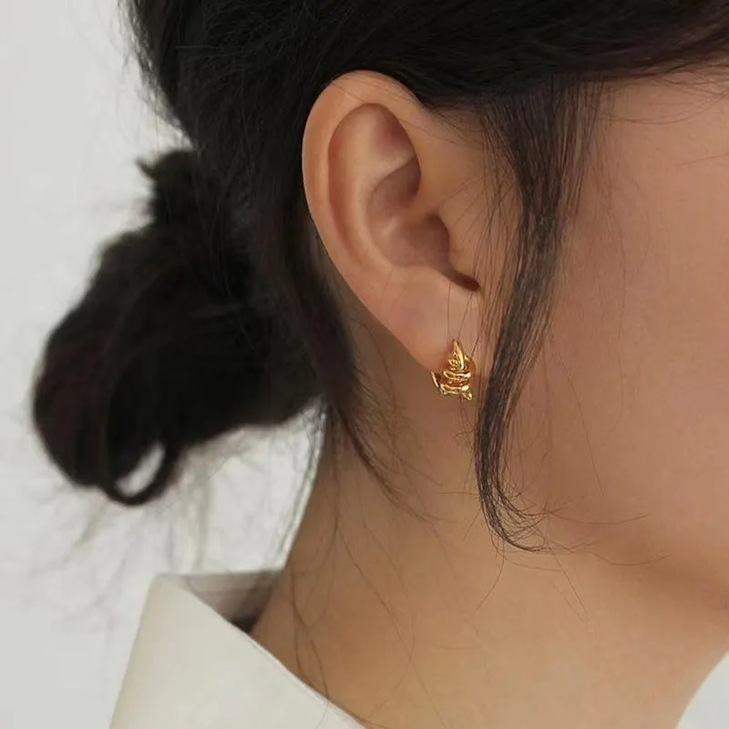 Spiral wound ear clip frosty style geometric earrings in gold colour on white background