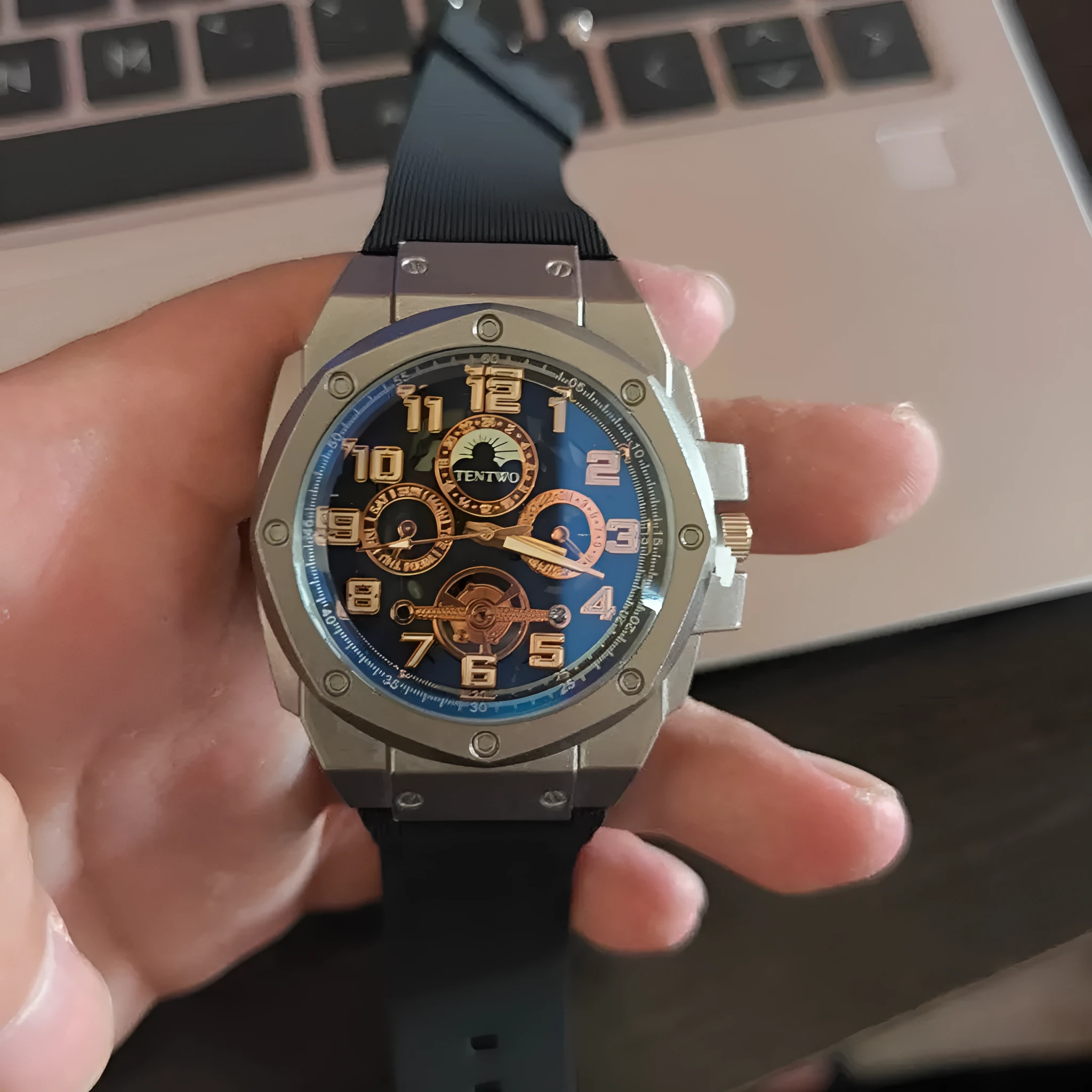 Four-ring Black And Silver Watch on a surface showing round black dial and interlocking metal bracelet