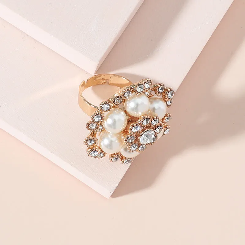 Simple retro fashion ring with pearl inlay and rhinestone flower shape in white KC gold on a flat surface