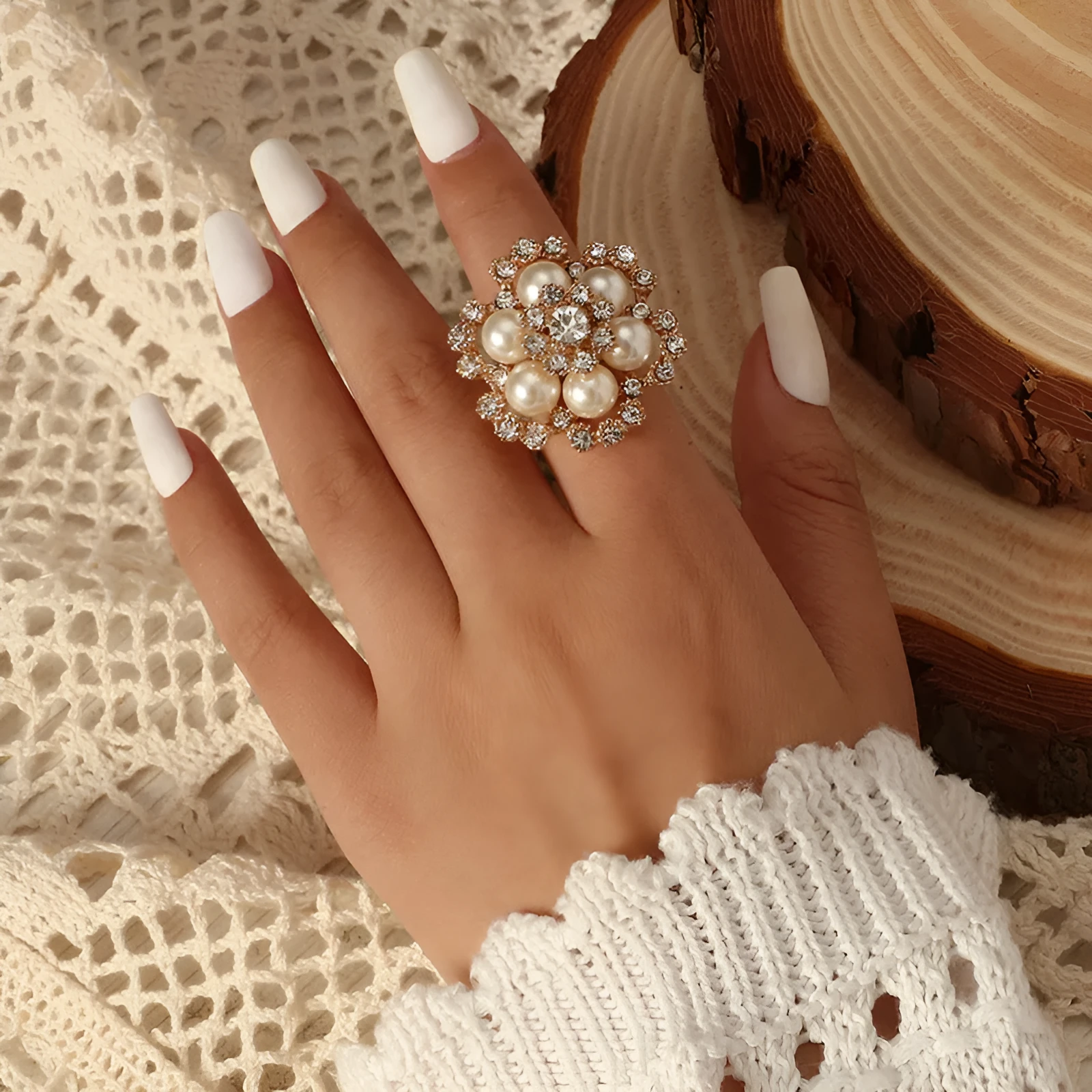 Simple retro fashion ring with pearl inlay and rhinestone flower shape in white KC gold on a flat surface