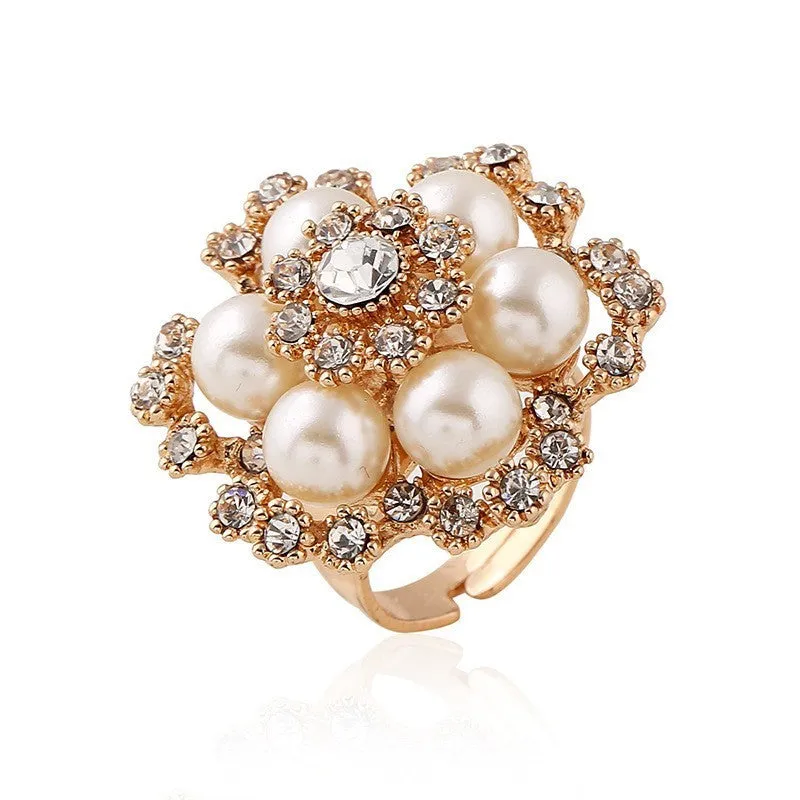 Simple retro fashion ring with pearl inlay and rhinestone flower shape in white KC gold on a flat surface
