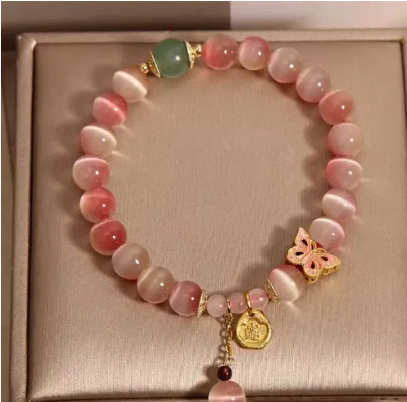 Close-up of a women's bracelet with a pink opal butterfly charm on an electroplated chain.