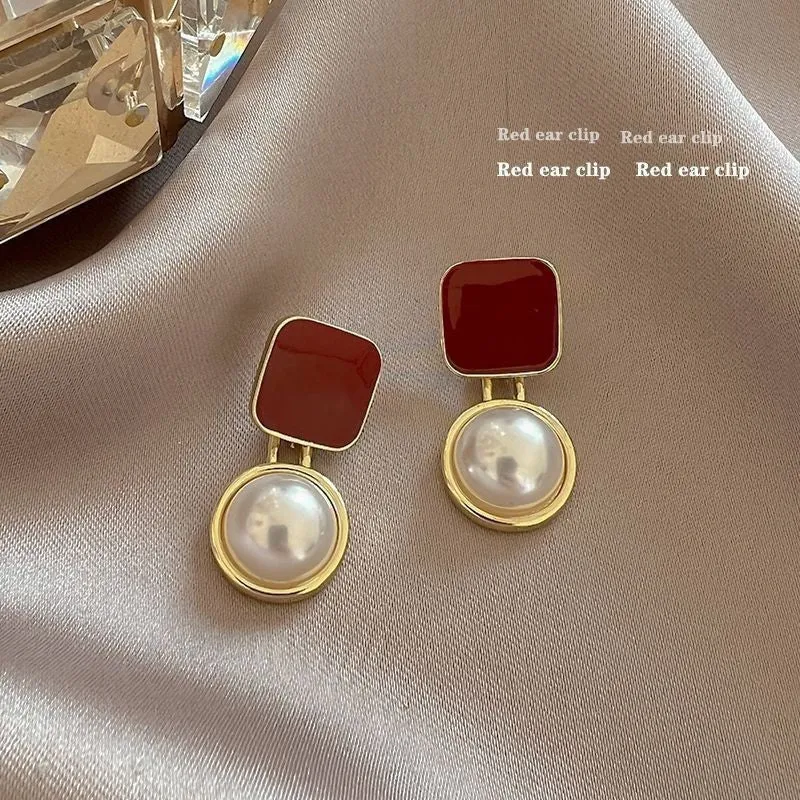Red and blue geometric alloy stud earrings with pearl centre on neutral background
