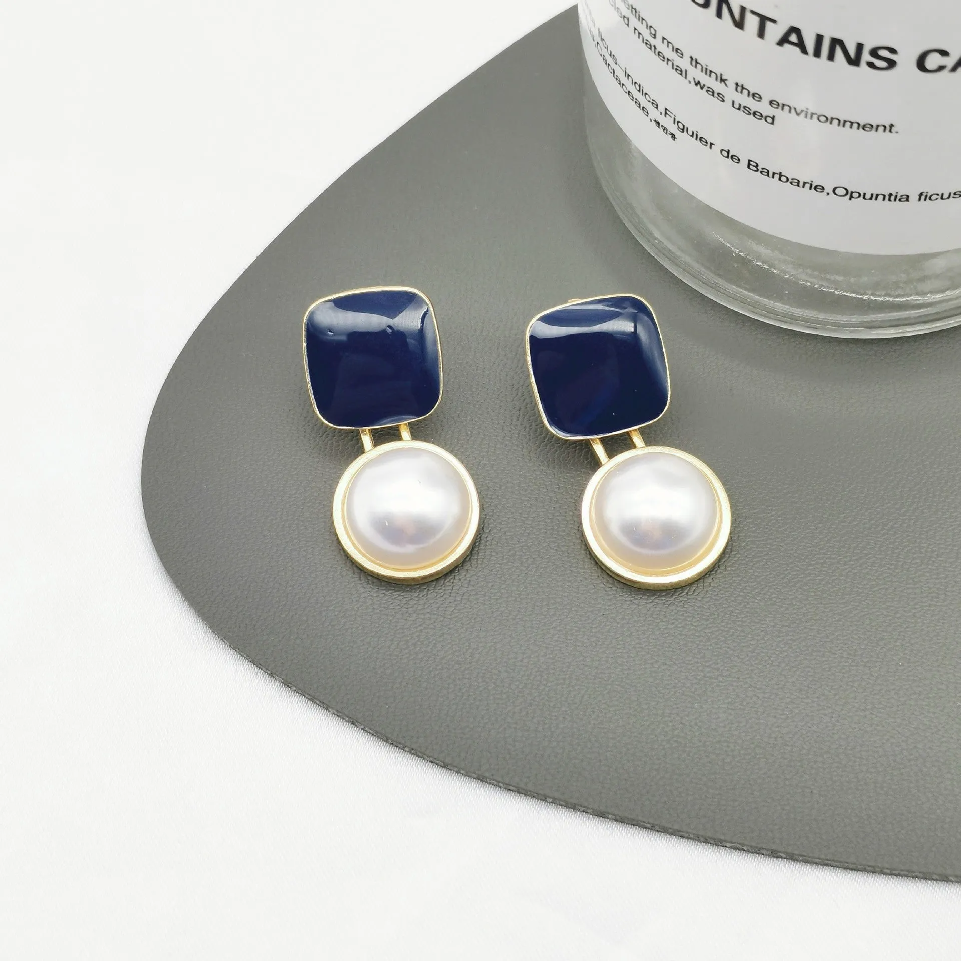 Red and blue geometric alloy stud earrings with pearl centre on neutral background