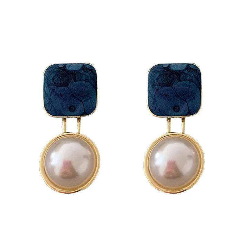 Red and blue geometric alloy stud earrings with pearl centre on neutral background