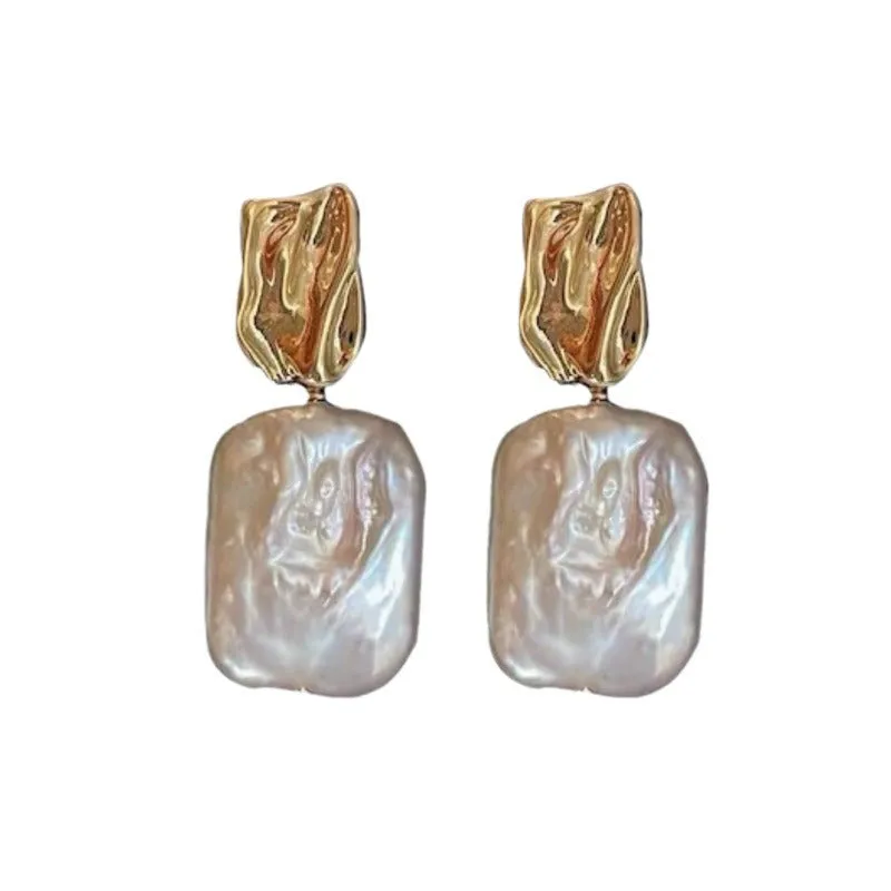 A pair of square stud earrings with a natural freshwater pearl set in a geometric alloy frame, shown in purple.