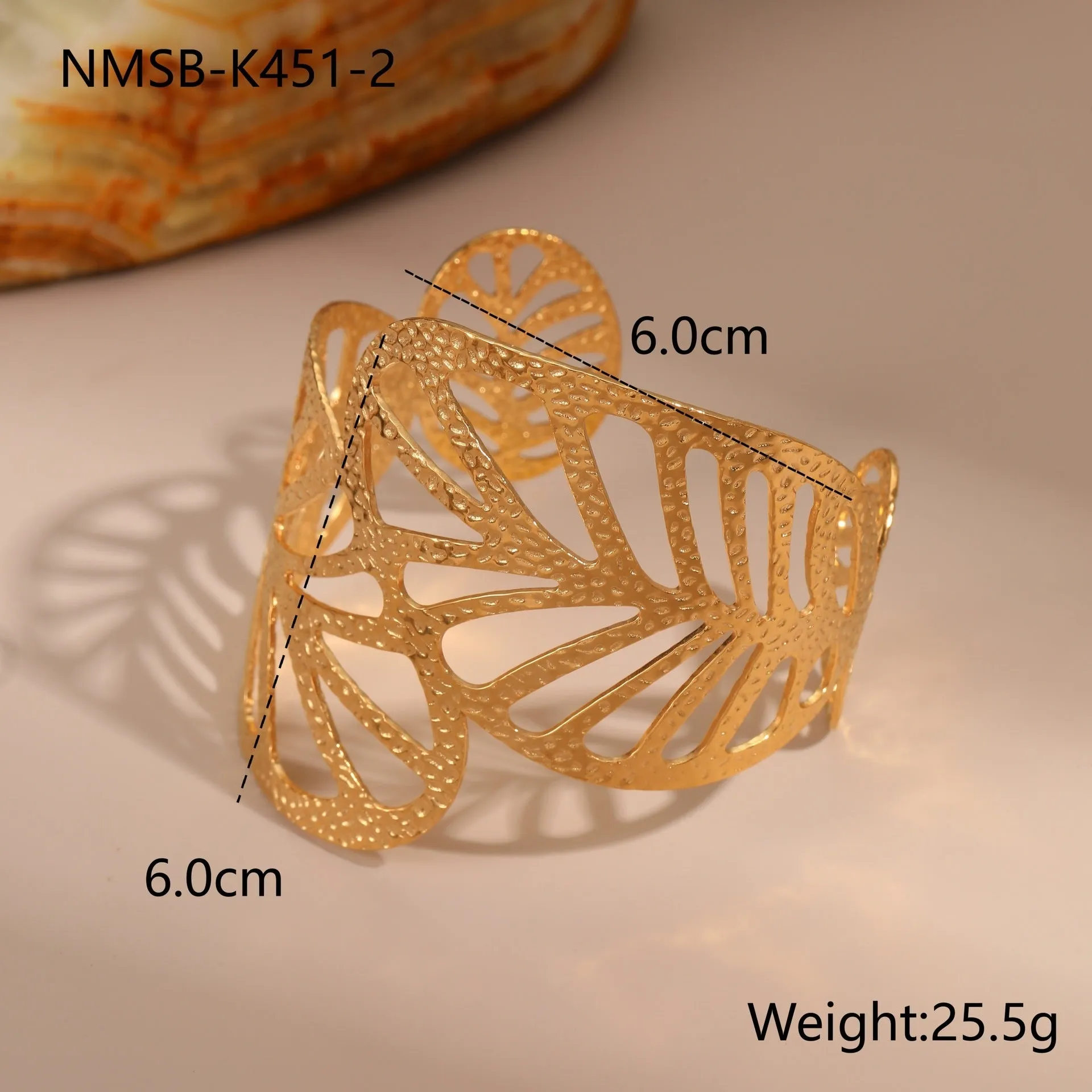 Gold stainless steel wristband with geometric leaf bow design on white background