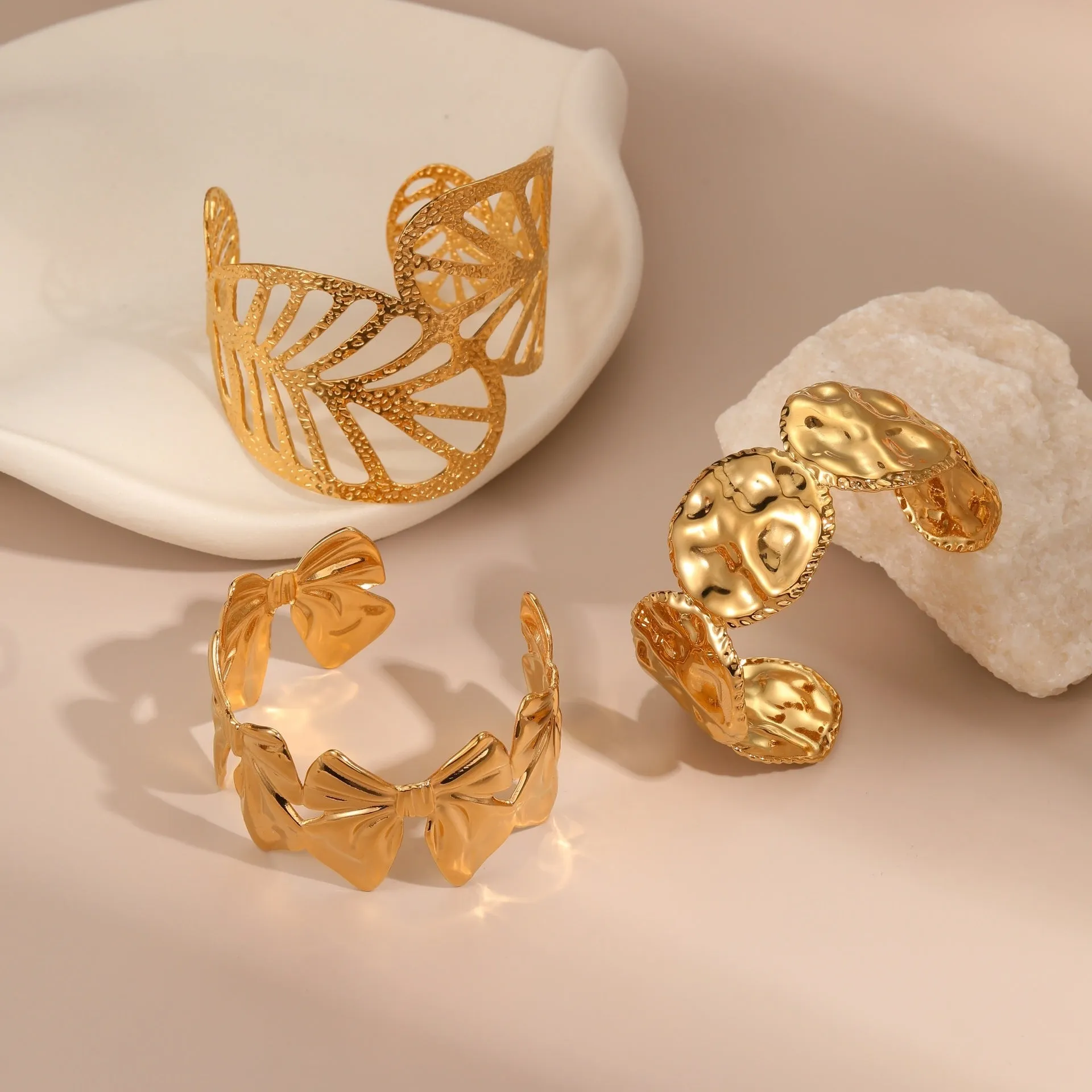 Gold stainless steel wristband with geometric leaf bow design on white background