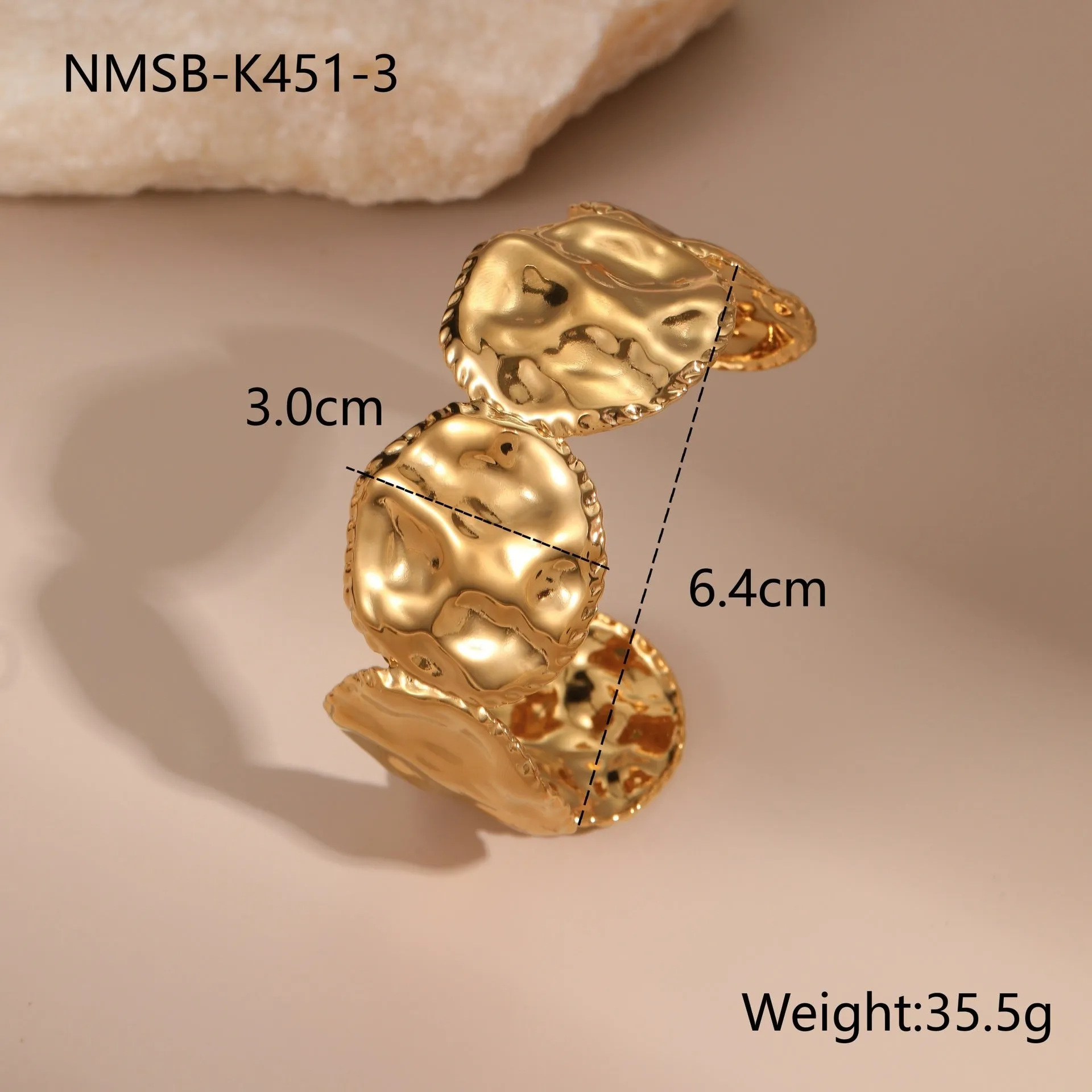 Gold stainless steel wristband with geometric leaf bow design on white background