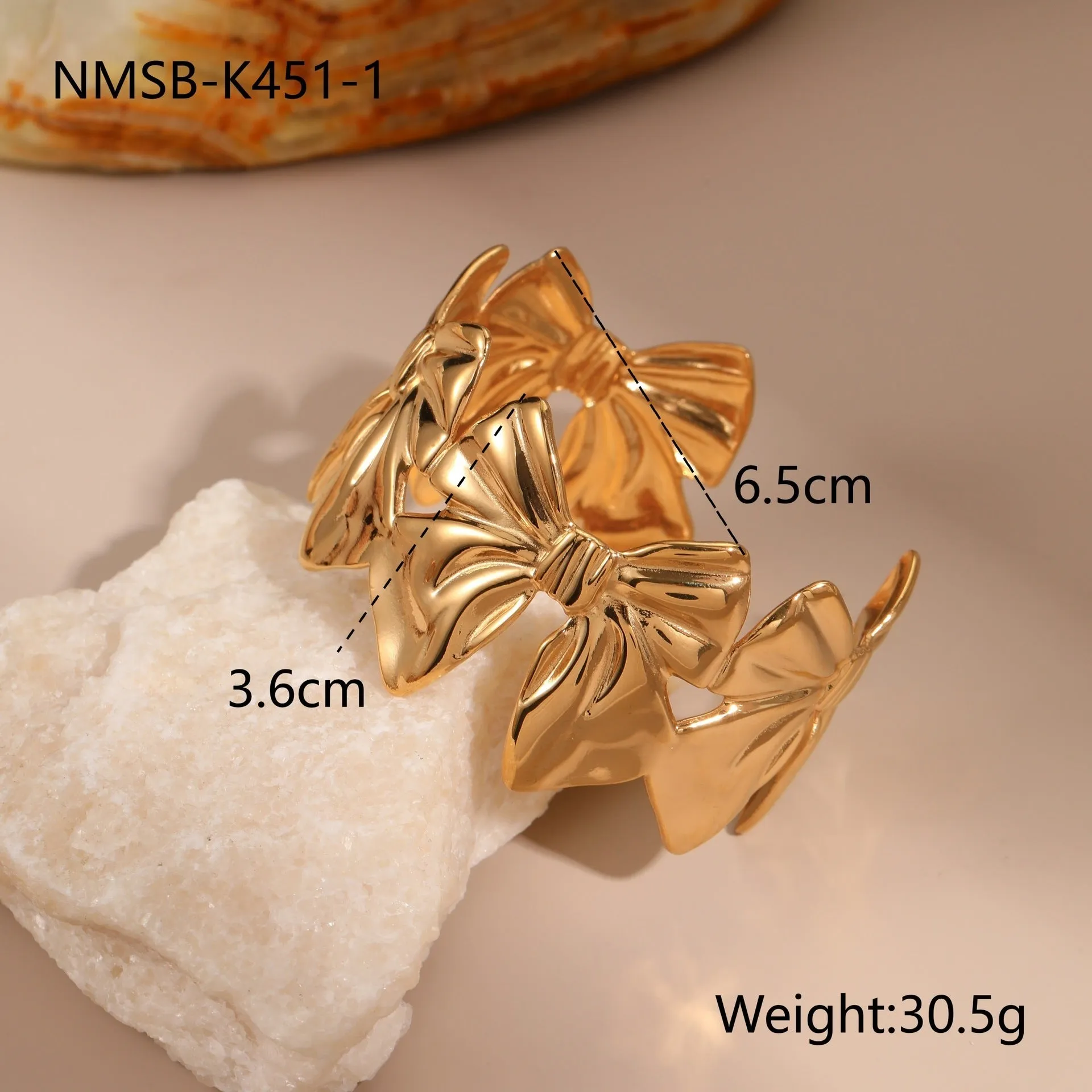 Gold stainless steel wristband with geometric leaf bow design on white background
