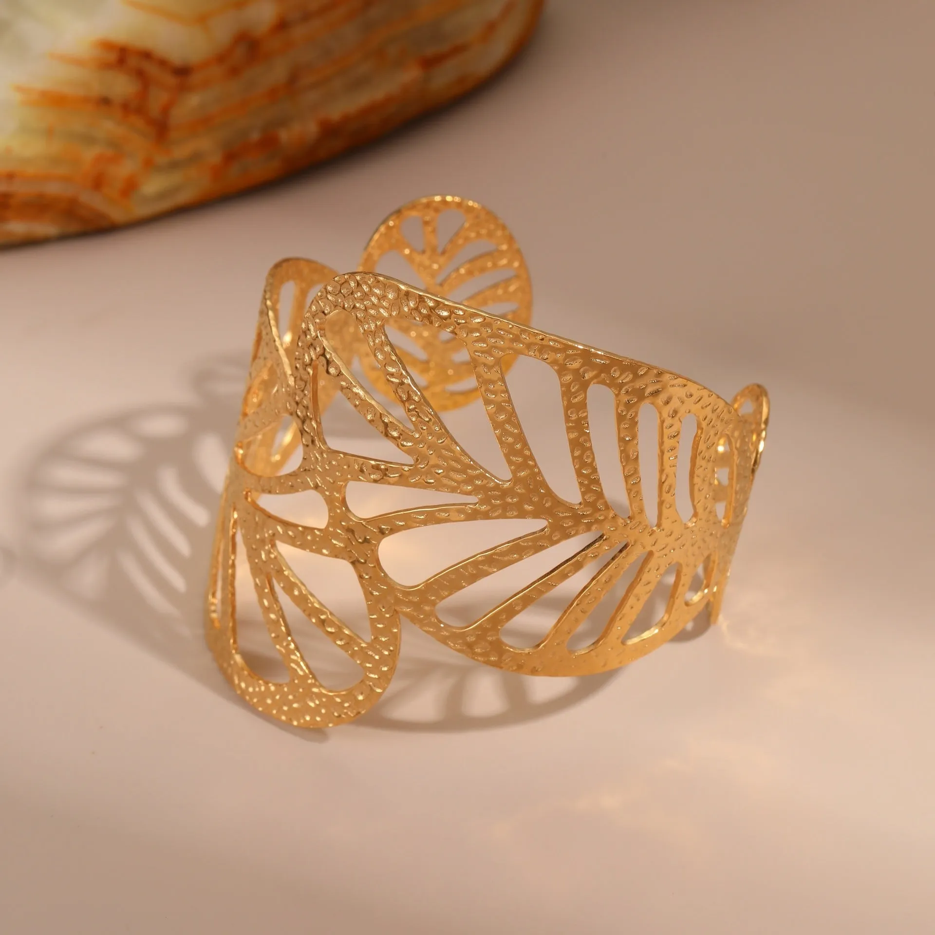 Gold stainless steel wristband with geometric leaf bow design on white background