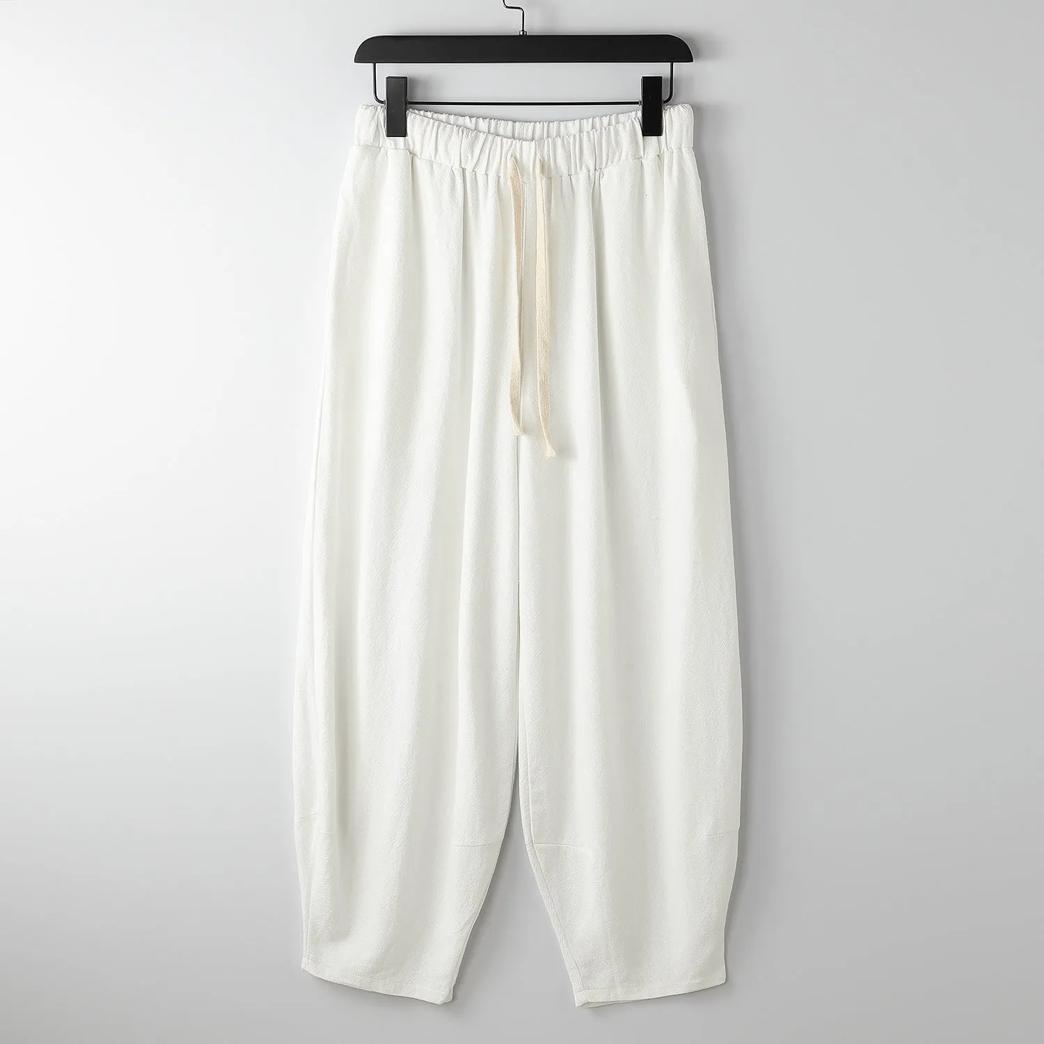 Linen harem pants for men with loose tapered fit and ankle-tied cuffs, shown in grey.