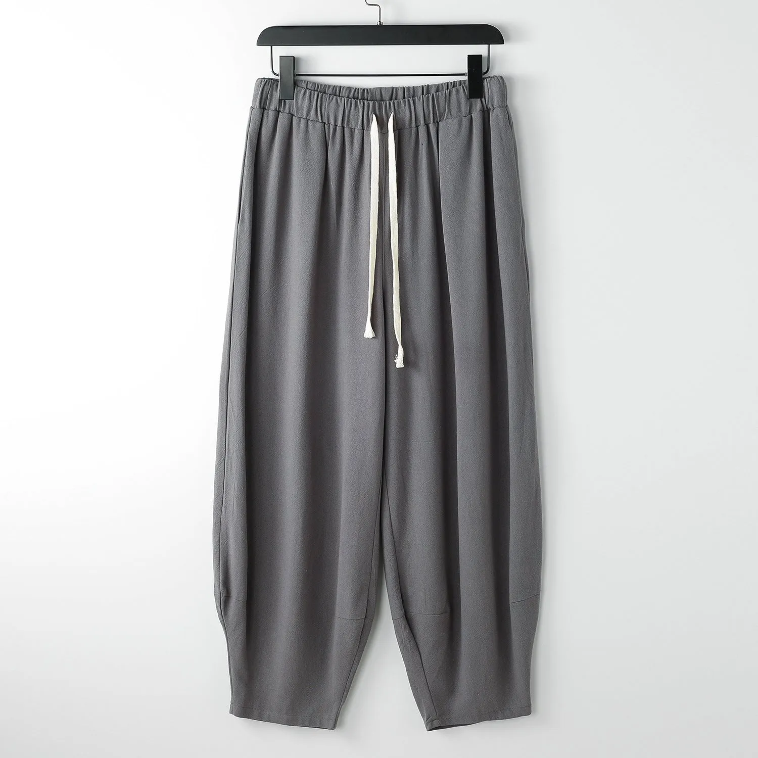 Linen harem pants for men with loose tapered fit and ankle-tied cuffs, shown in grey.