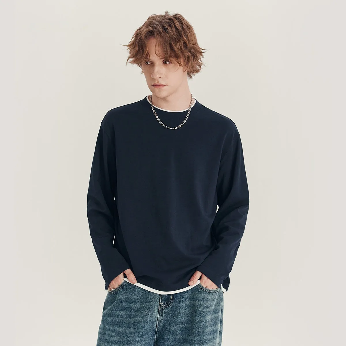 Man wearing a loose fit long-sleeved round neck t-shirt in a solid colour