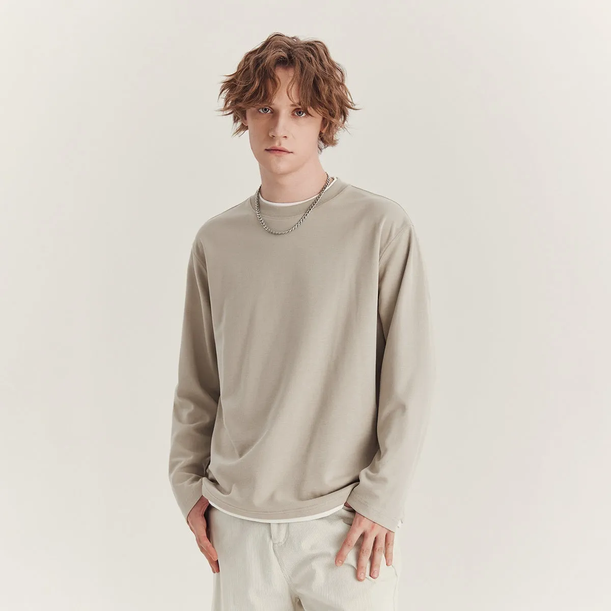Man wearing a loose fit long-sleeved round neck t-shirt in a solid colour