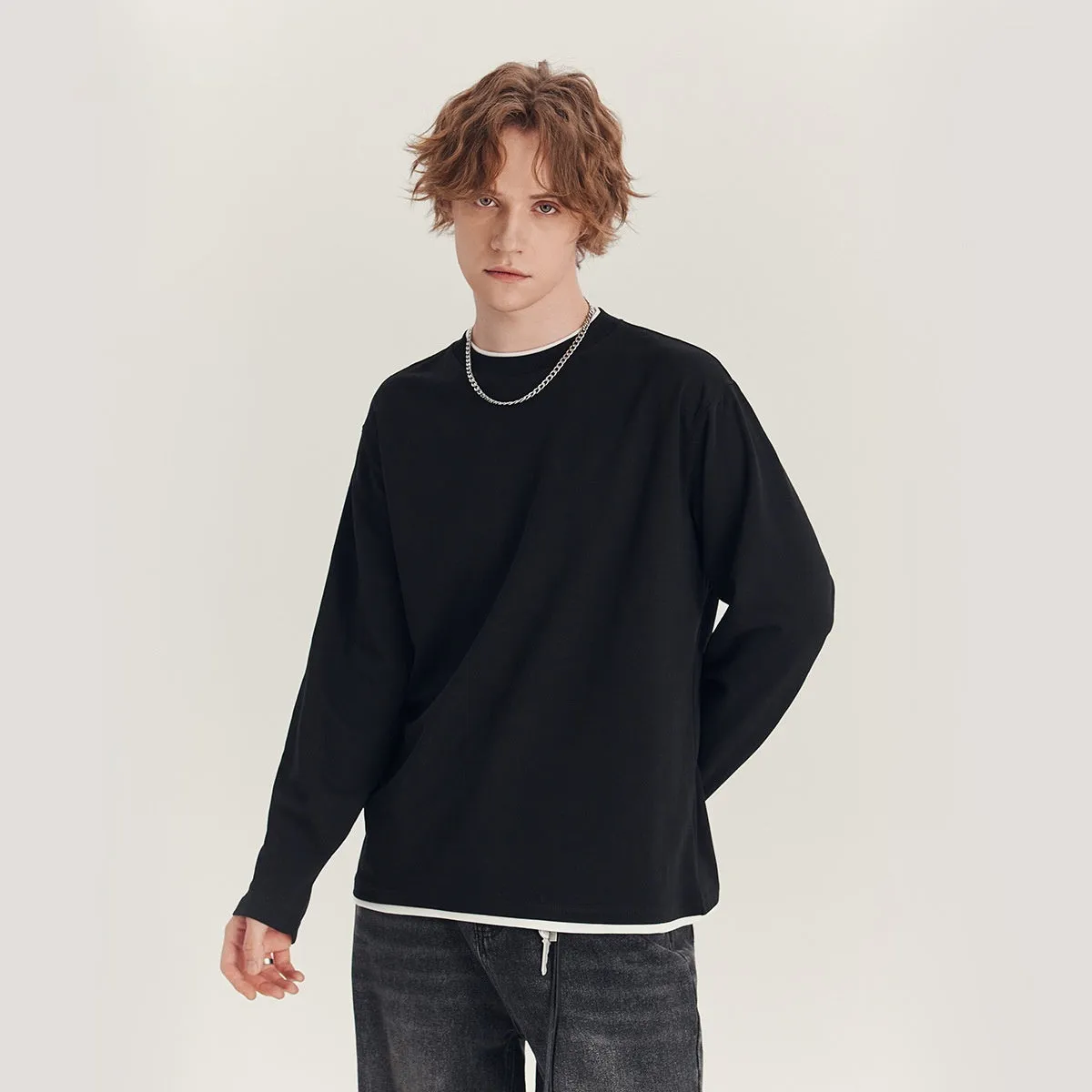 Man wearing a loose fit long-sleeved round neck t-shirt in a solid colour
