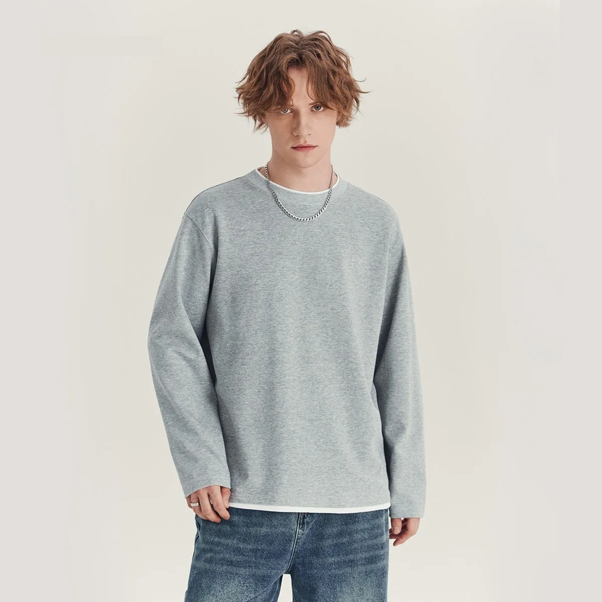 Man wearing a loose fit long-sleeved round neck t-shirt in a solid colour