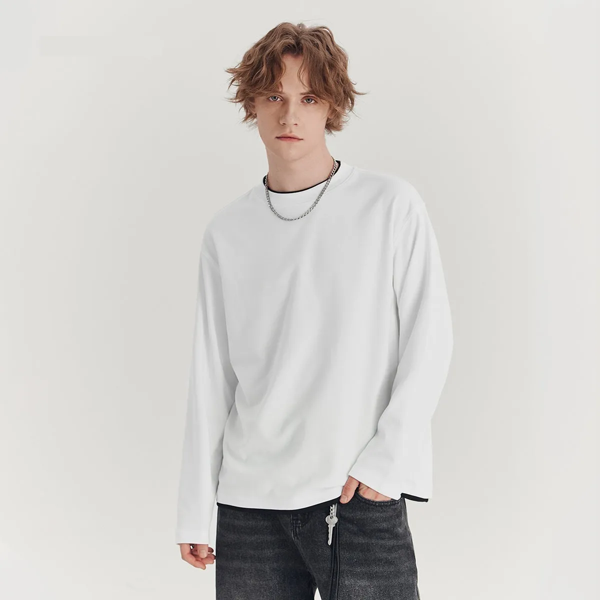 Man wearing a loose fit long-sleeved round neck t-shirt in a solid colour