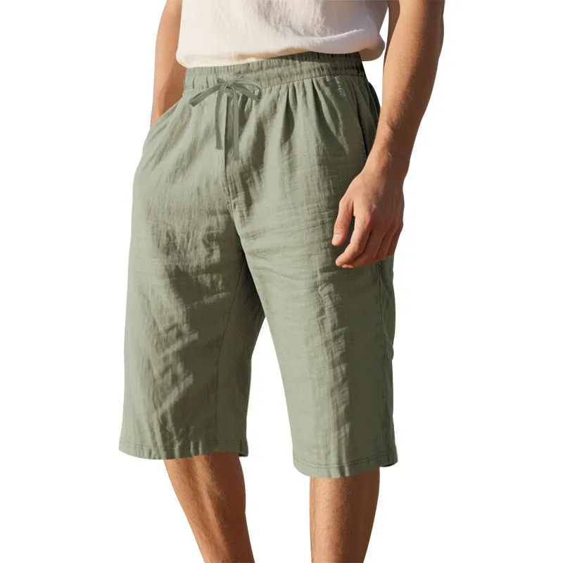 Men's light khaki linen shorts with a drawstring waistband and loose, cropped leg fit.