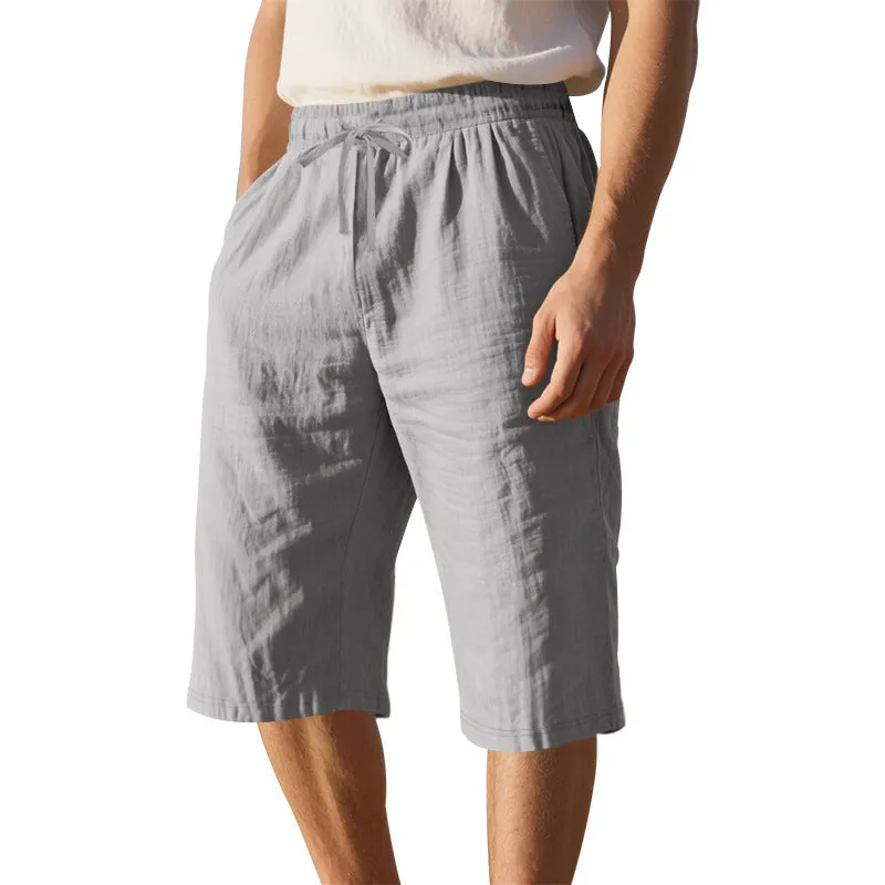 Men's light khaki linen shorts with a drawstring waistband and loose, cropped leg fit.