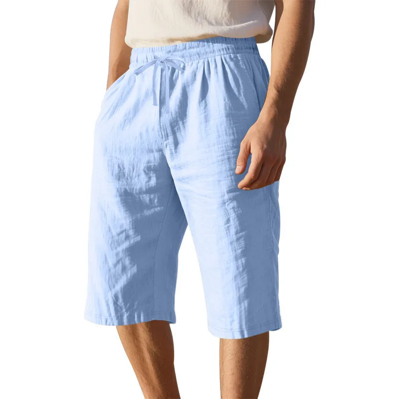 Men's light khaki linen shorts with a drawstring waistband and loose, cropped leg fit.