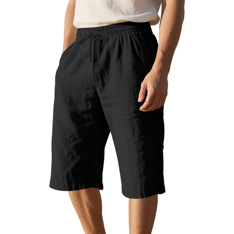 Men's light khaki linen shorts with a drawstring waistband and loose, cropped leg fit.