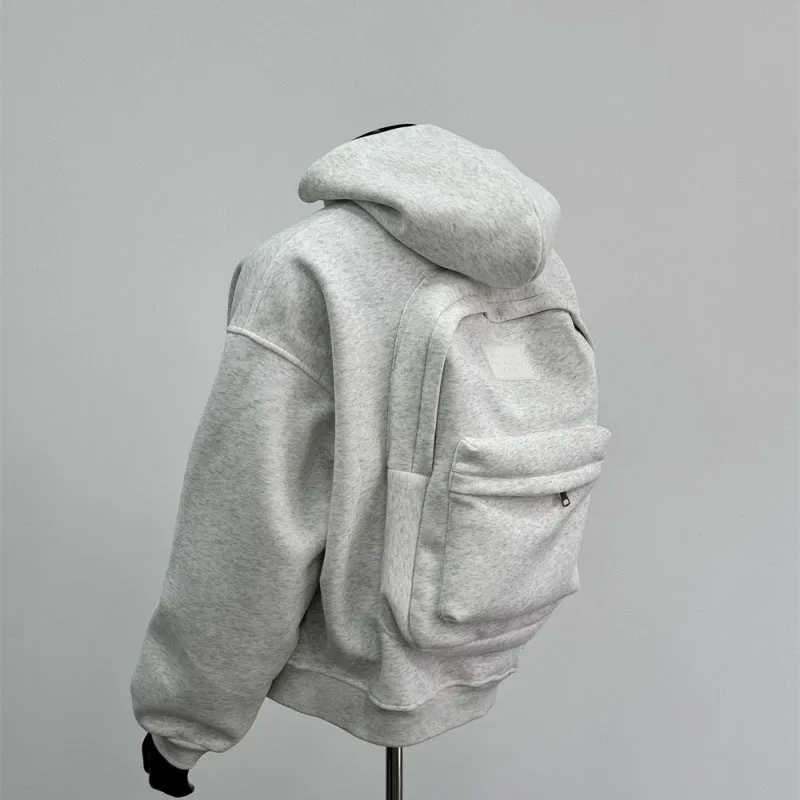 Man wearing a light gray hooded coat with a schoolbag design detail on the back.
