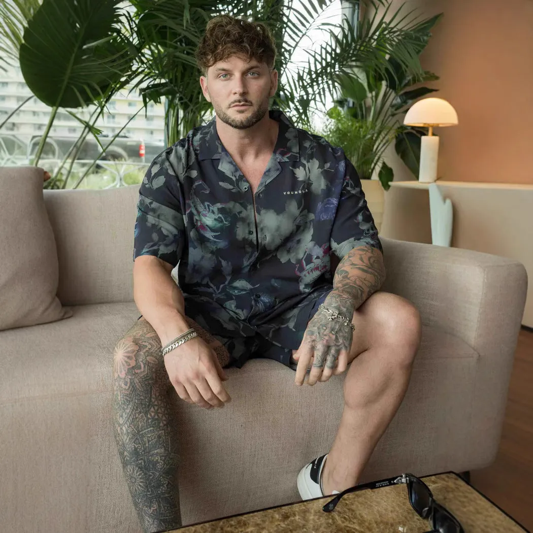 Man wearing a loose, short-sleeved printed floral top in a light colour.