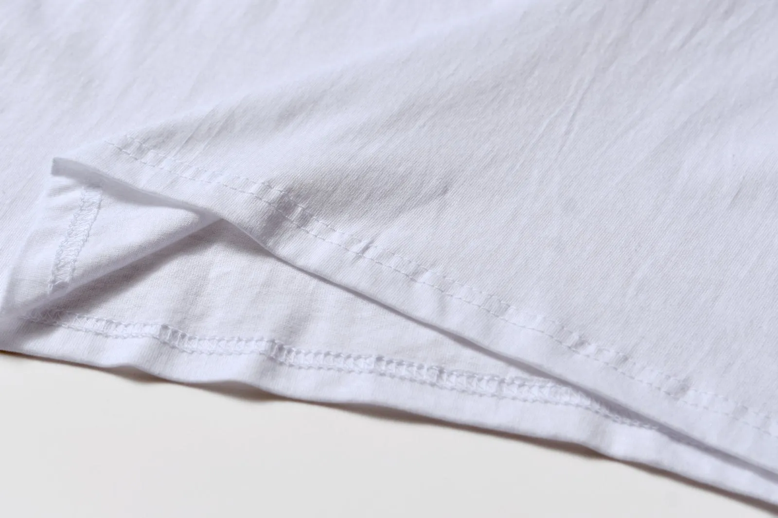 White cotton pullover overalls with short sleeves and a round neck, shown on a hanger.